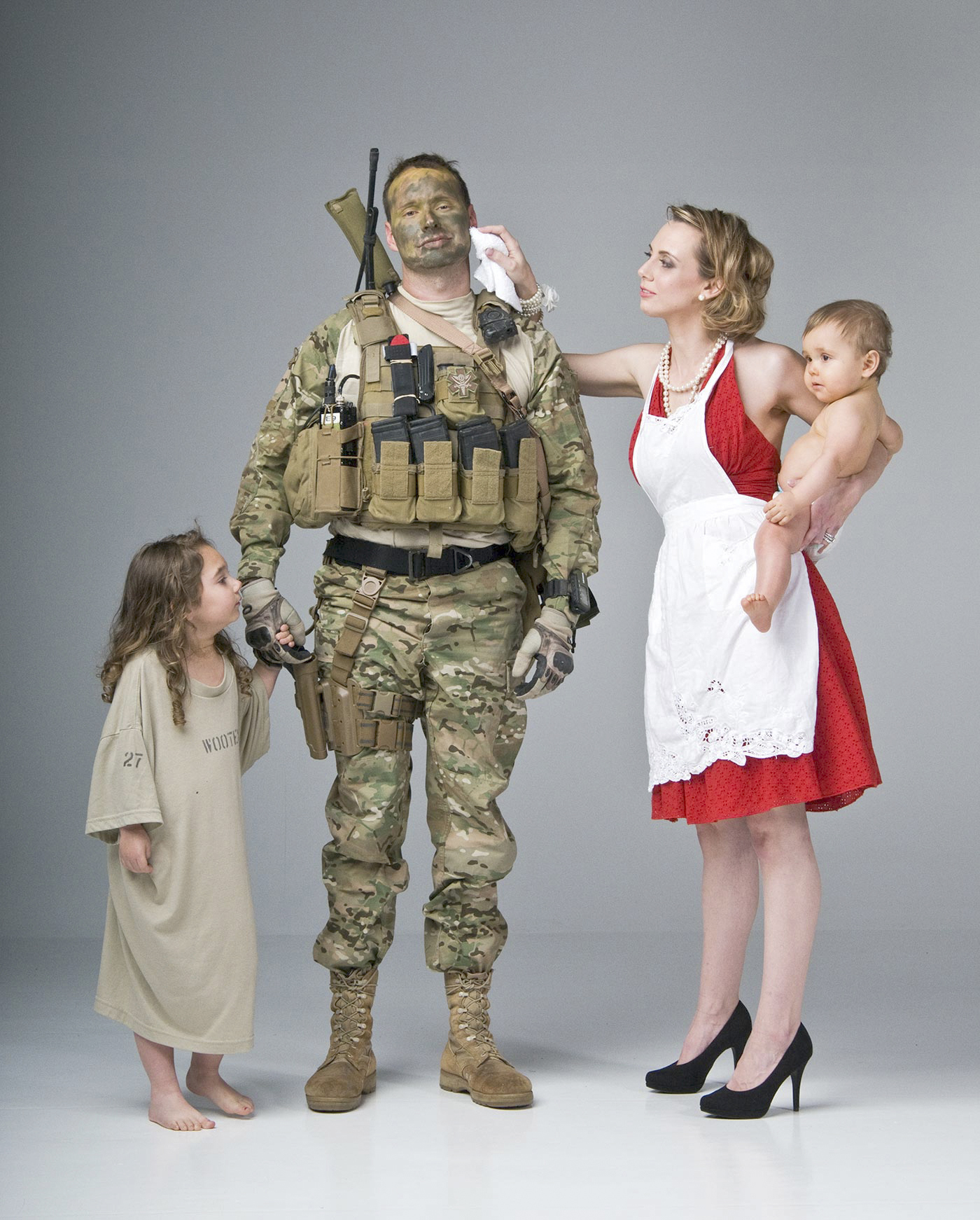 A military family of four standing together at golden hour.