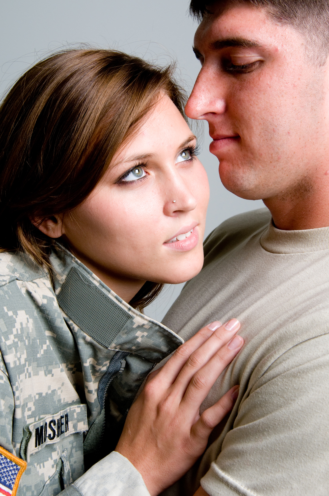 A pregnant woman's belly cradled by her husband in uniform.